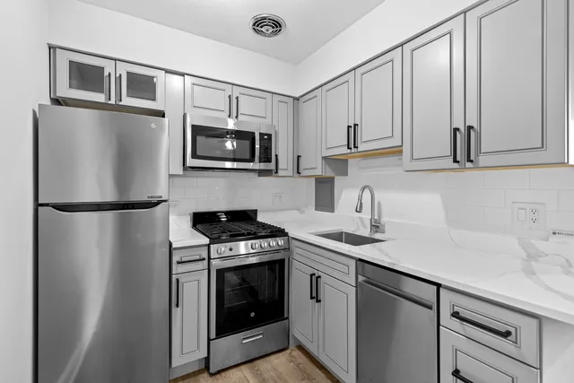 a kitchen with stainless steel appliances granite countertop a refrigerator a stove a sink and a microwave