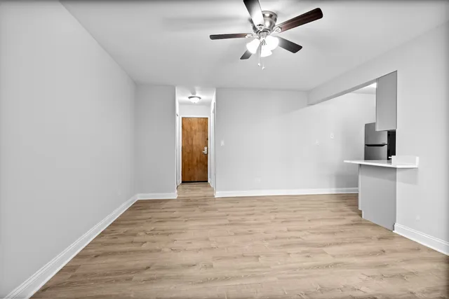 a view of an empty room with window and wooden floor