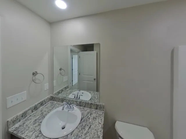 a bathroom with a granite countertop sink toilet and mirror