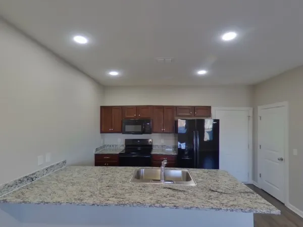a view of kitchen with stainless steel appliances wooden floor and chair