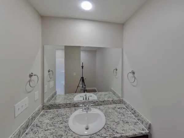 a bathroom with a granite countertop sink a mirror and shower