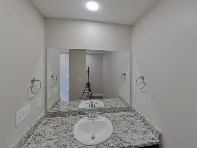 a bathroom with a granite countertop sink a mirror and shower