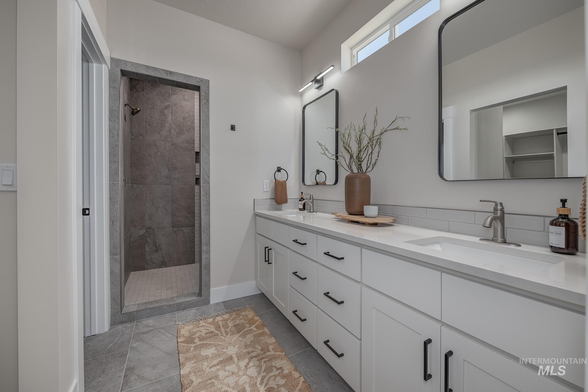 1371 Hansen Road Weiser, ID 83672 - Photo 20 of 44 Dual vanity with white cabinetry and integrated sinks, a tiled walk-in shower, and a transom window
