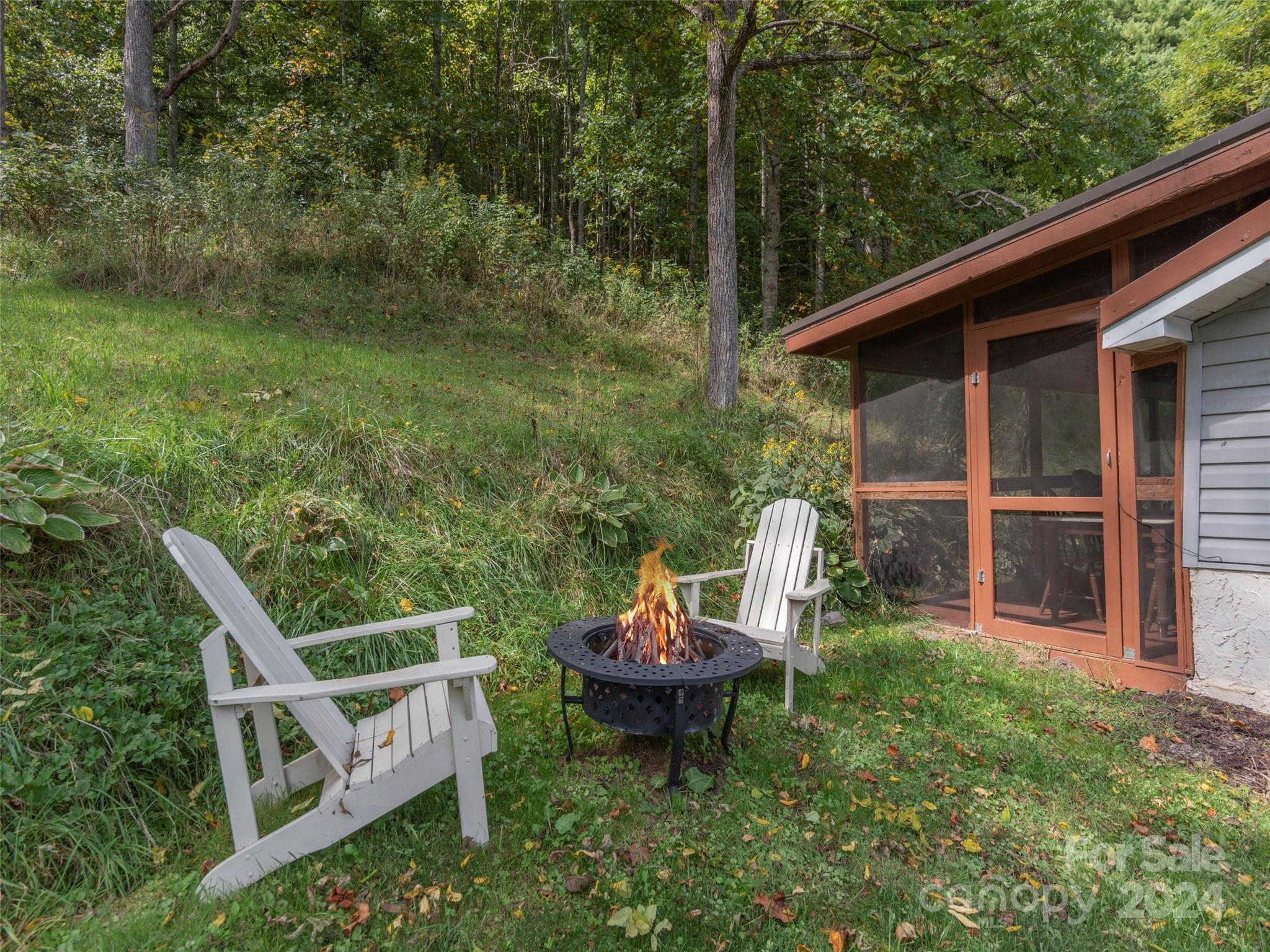 883 Price Town Road Clyde, NC 28721 - Photo 23 of 34 a view of a chair and fire pit in the backyard