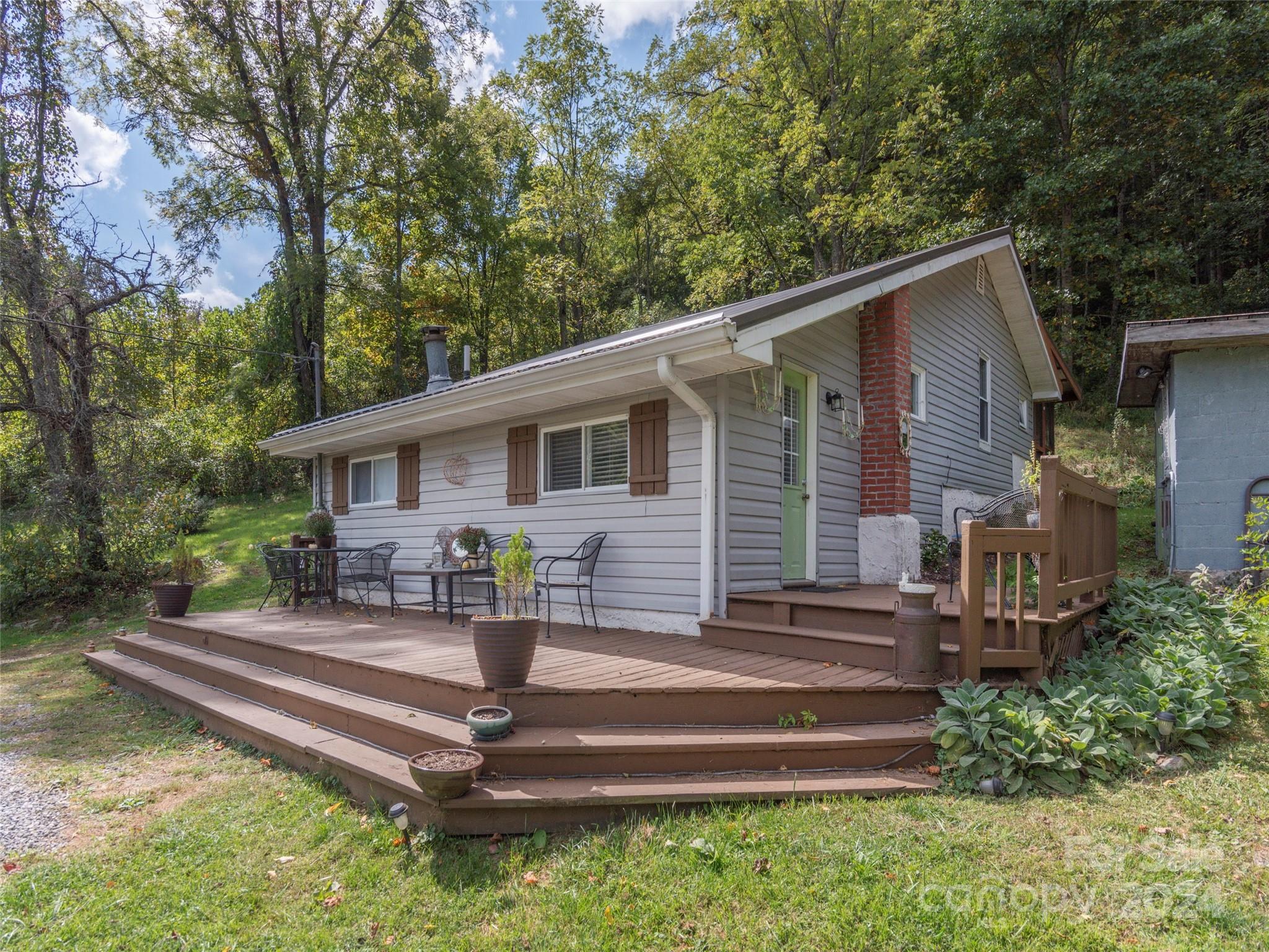 883 Price Town Road Clyde, NC 28721 - Photo 3 of 34 a front view of a house with a garden and chairs
