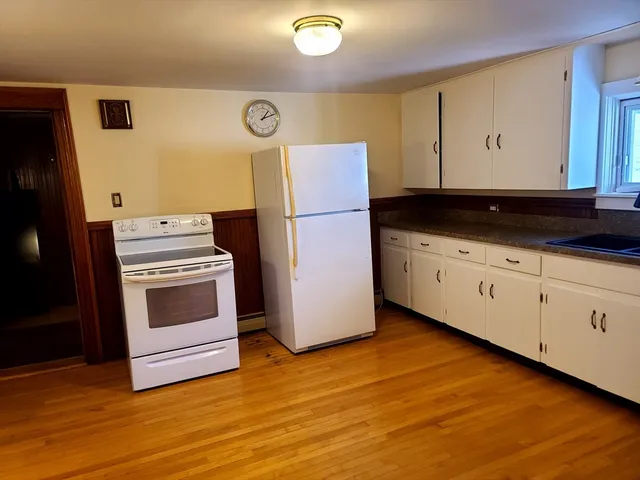 a kitchen with granite countertop white cabinets and white appliances