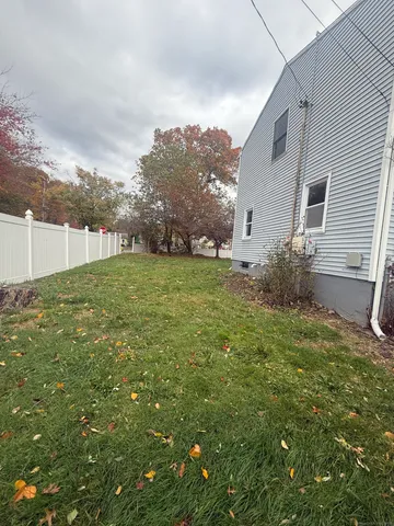 a backyard of a house with plants and large tree