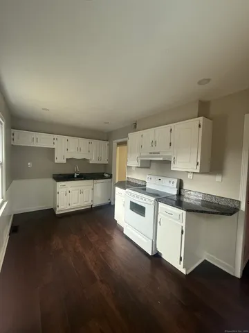 a kitchen with stainless steel appliances a sink a stove and white cabinets