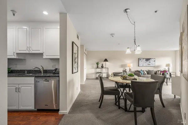a view of a dining room and livingroom with furniture wooden floor kitchen chandelier
