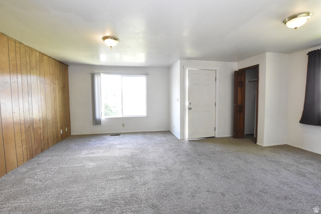290 West 600 North Logan, UT 84321 - Photo 36 of 45 Spacious room featuring wood paneling, white painted walls, and gray carpet