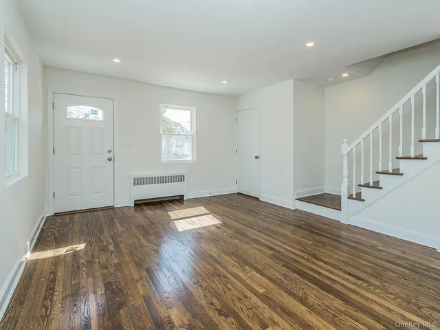 a view of empty room with wooden floor and windows