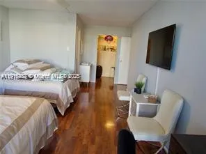 a spacious bedroom with a bed a flat screen tv and a couch