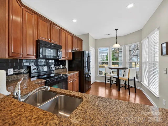 a kitchen with stainless steel appliances granite countertop a refrigerator a sink a stove and cabinets