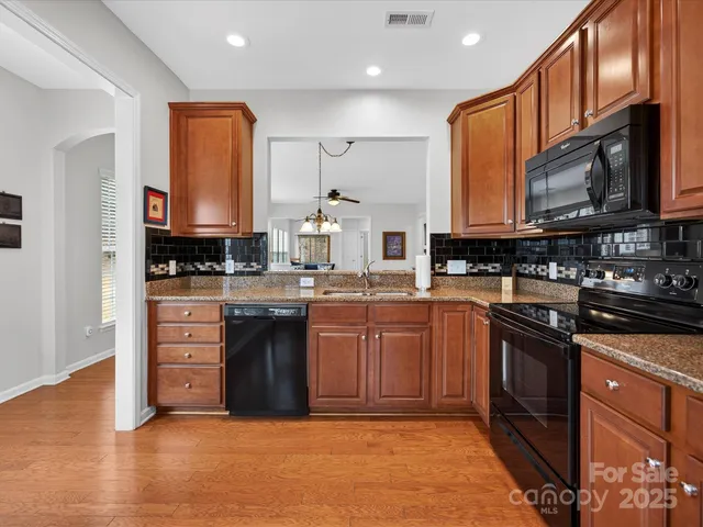 a kitchen with stainless steel appliances granite countertop a stove a sink dishwasher and a microwave oven with wooden cabinets