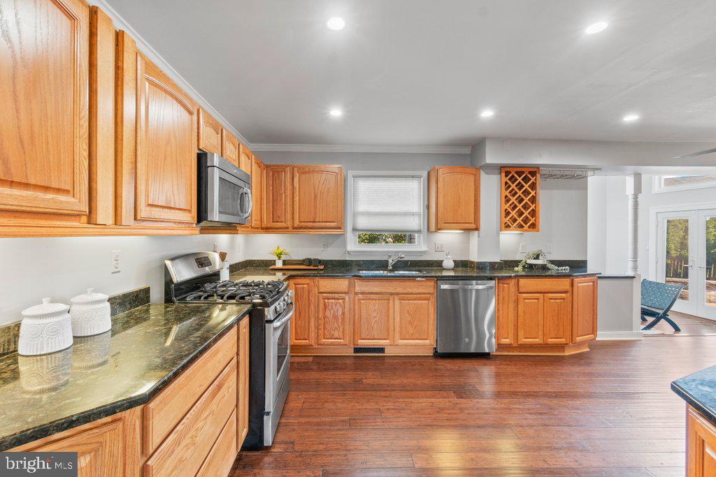 4426 Camellia Road Baltimore, MD 21236 - Photo 11 of 51 a kitchen with stainless steel appliances granite countertop wooden cabinets a sink a stove a dining table and chairs with wooden floor