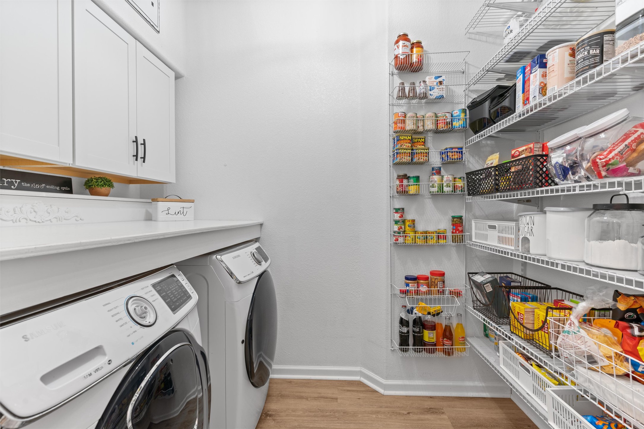 338 Altamont Street Hutto, TX 78634 - Photo 13 of 40 Laundry room featuring light wood-type flooring, washer and clothes dryer, and cabinet space
