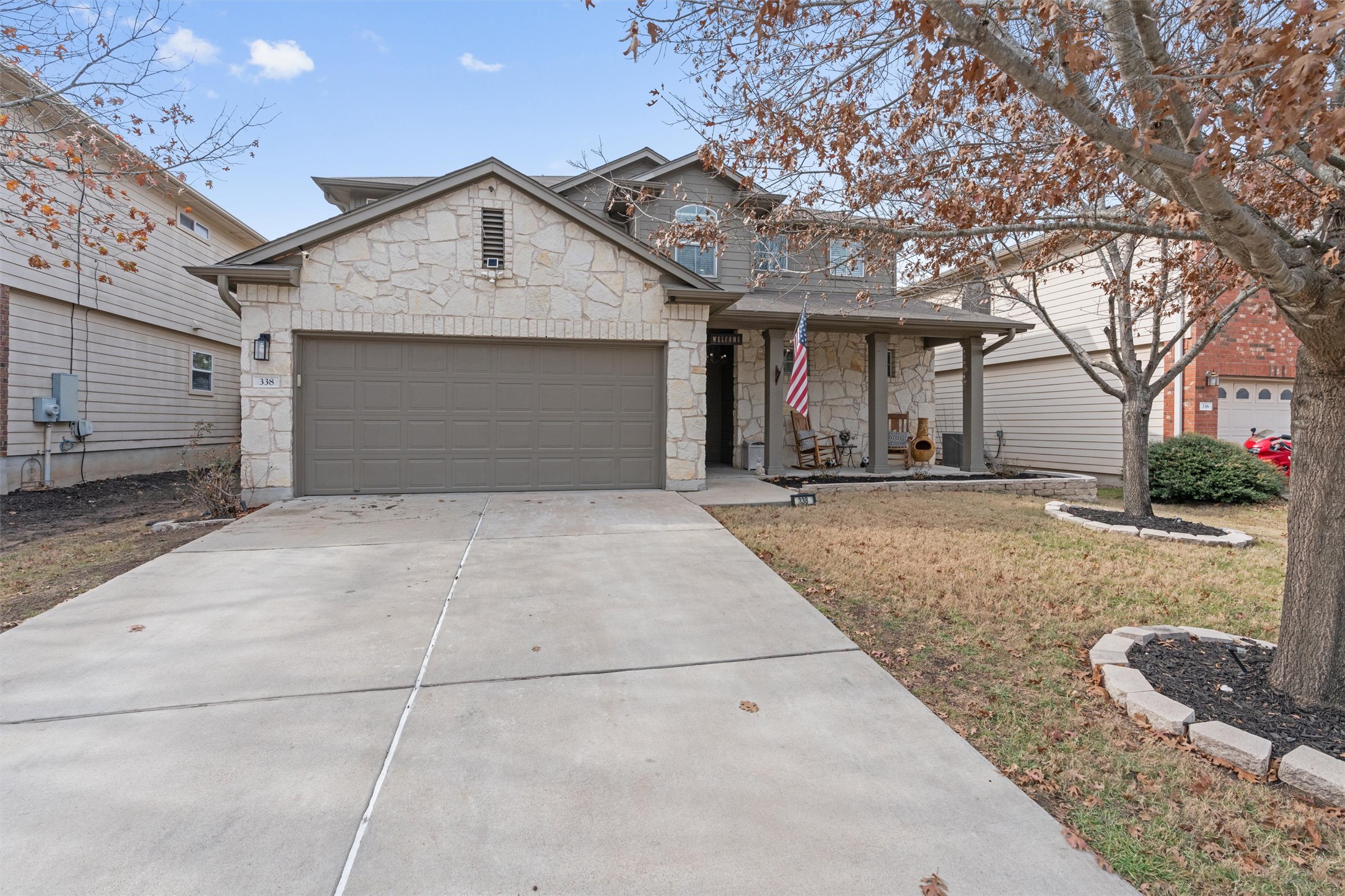 338 Altamont Street Hutto, TX 78634 - Photo 2 of 40 View of front of house with stone siding, covered porch, driveway, a garage, and a front lawn