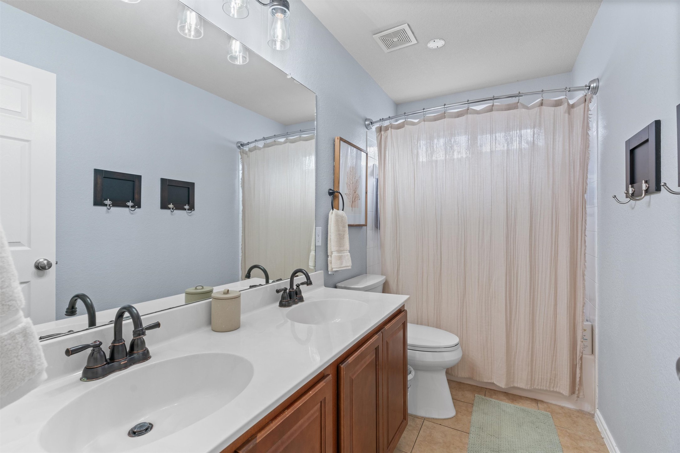 338 Altamont Street Hutto, TX 78634 - Photo 23 of 40 Full bathroom featuring double vanity, shower / bath combo with shower curtain, and light tile patterned floors