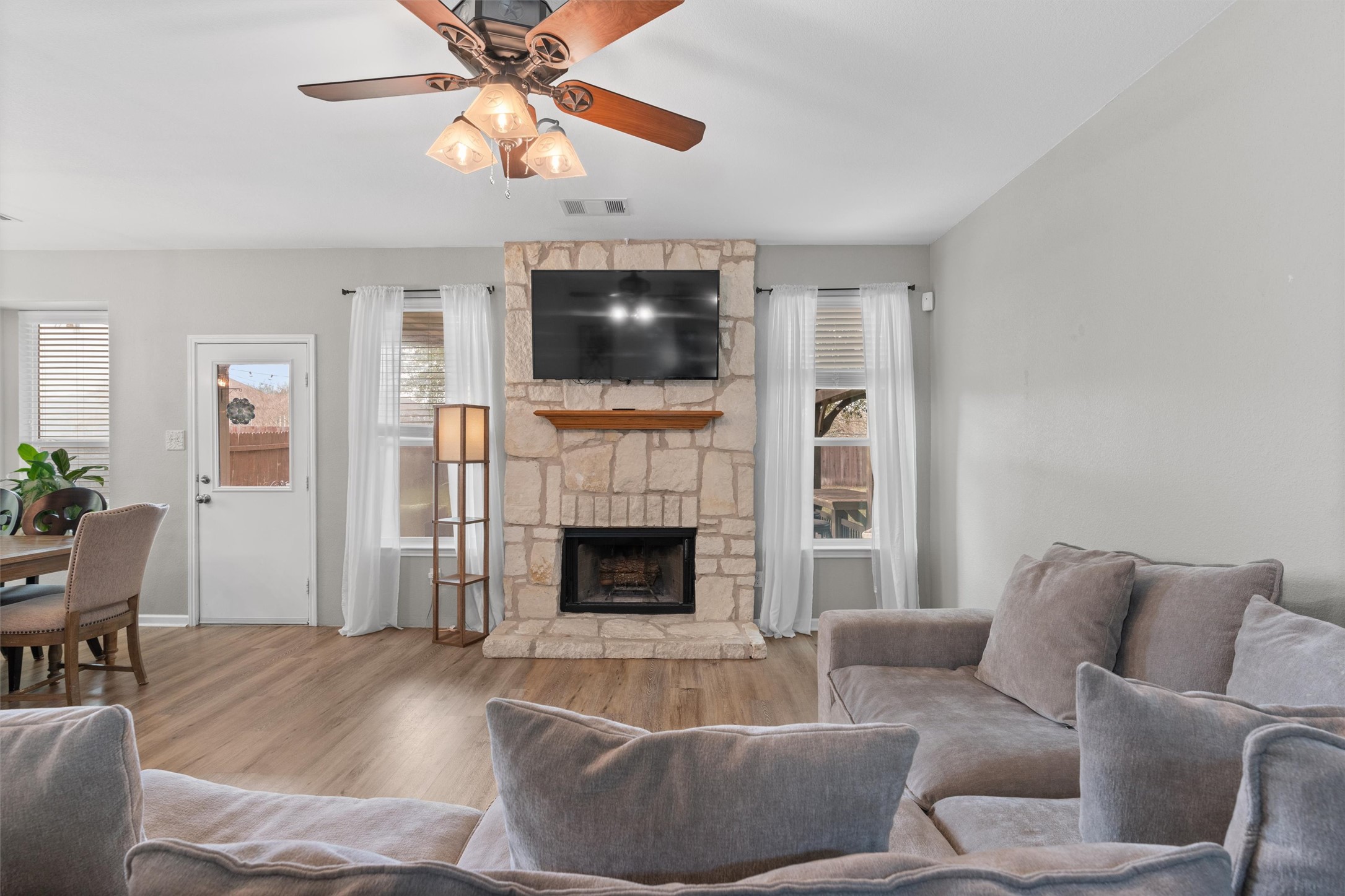 338 Altamont Street Hutto, TX 78634 - Photo 5 of 40 Living room with wood finished floors, ceiling fan, a stone fireplace, and healthy amount of natural light
