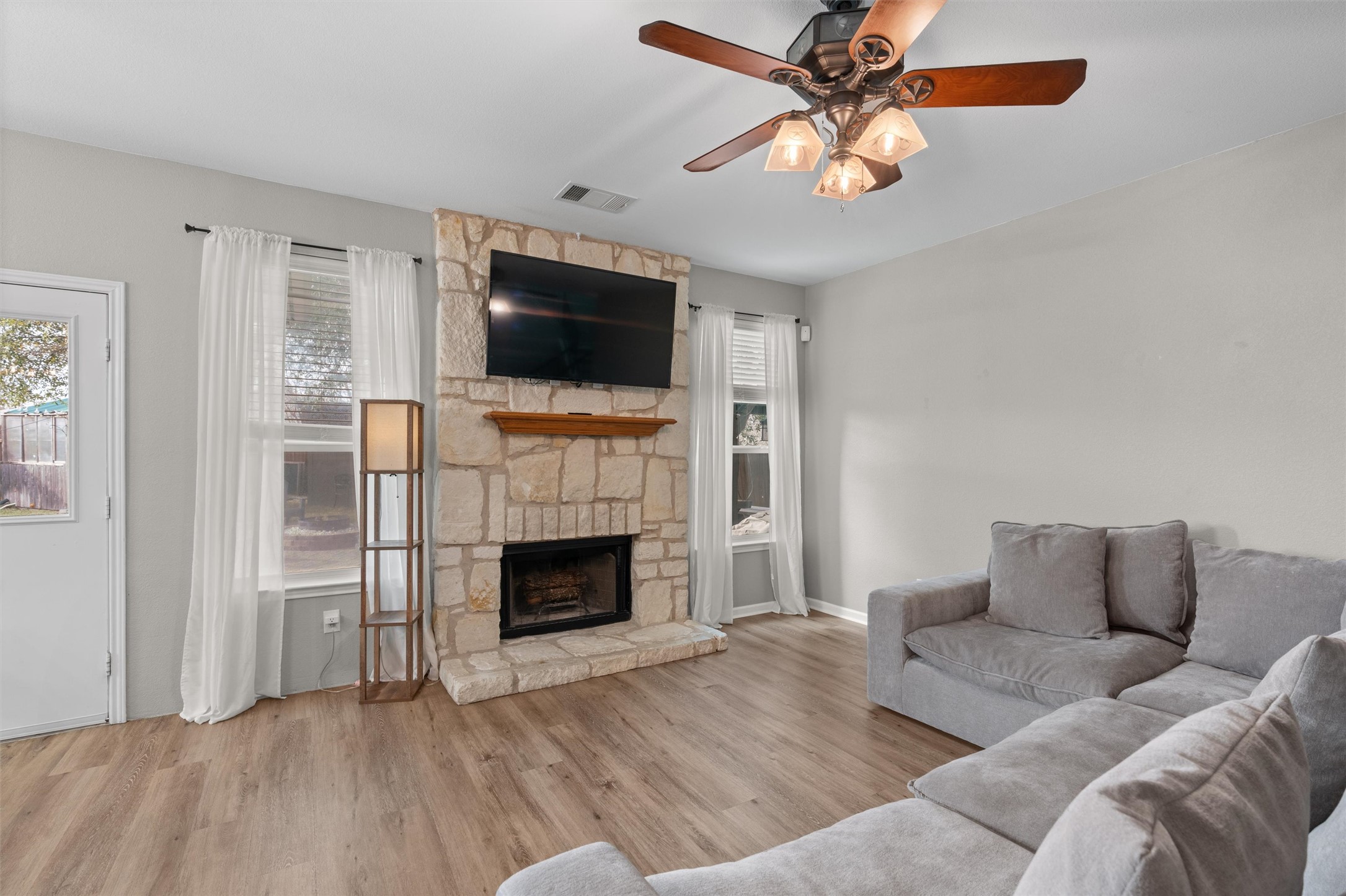 338 Altamont Street Hutto, TX 78634 - Photo 7 of 40 Living area with wood finished floors, a ceiling fan, and a fireplace