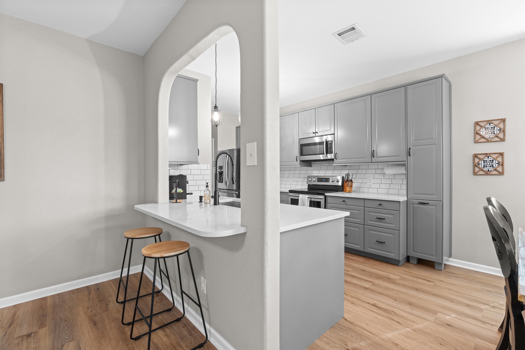 338 Altamont Street Hutto, TX 78634 - Photo 8 of 40 Kitchen featuring a breakfast bar area, gray cabinets, stainless steel appliances, light wood-style flooring, and decorative backsplash