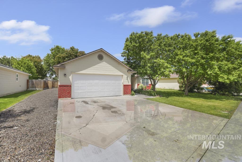 1183 Cortes Loop Twin Falls, ID 83301 - Photo 2 of 30 Single-story residence featuring light-colored siding, a red brick facade accent, an attached two-car garage, and a concrete driveway