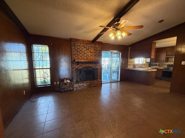 a view of an empty room with kitchen and a window