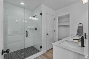907 West Bright Ridge Ln Street, Unit 1430 St. George, UT 84790 - Photo 18 of 19 Bathroom featuring a glass-enclosed shower with white subway tile walls and dark mosaic floor, dual vanity with undermount sinks, and black fixtures