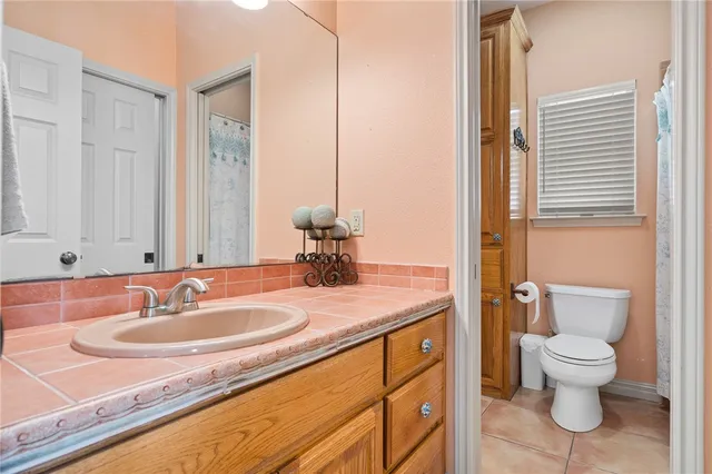 a bathroom with a granite countertop sink a toilet and a mirror