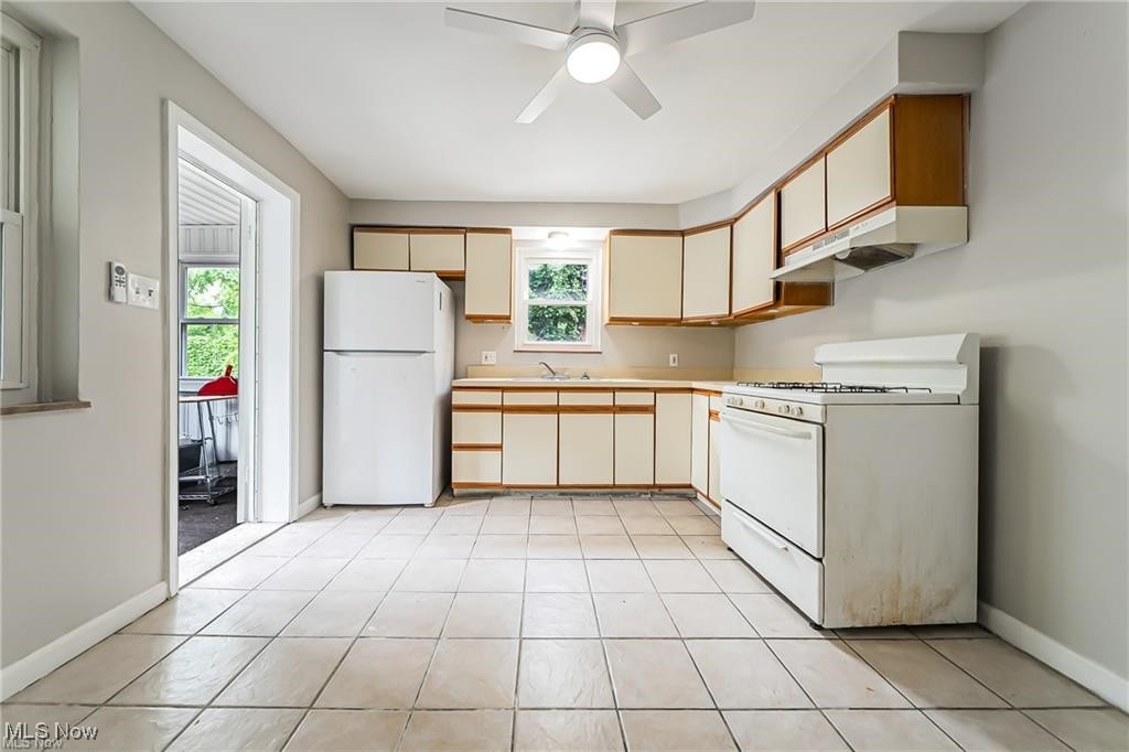 3837 Mayfield Road Cleveland, OH 44121 - Photo 6 of 29 Kitchen with white appliances, light countertops, under cabinet range hood, brown cabinetry, and a ceiling fan