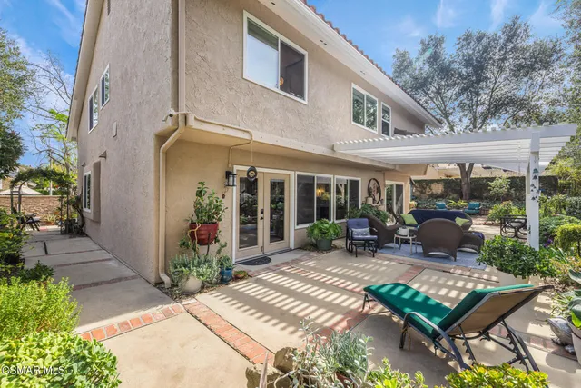 a view of a patio with table and chairs potted plants and floor to ceiling window and potted plants