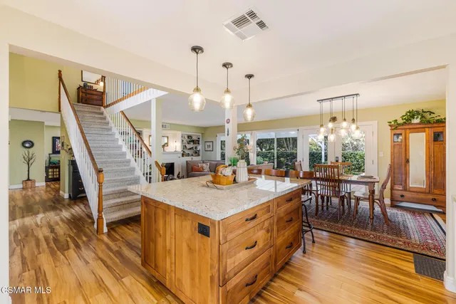 a large kitchen with stainless steel appliances a refrigerator a sink dishwasher a stove and white cabinets with wooden floor