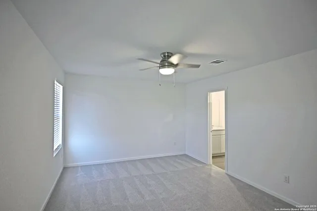 an empty room with windows and fan