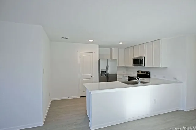 a view of a kitchen with stainless steel appliances wooden cabinets and a refrigerator
