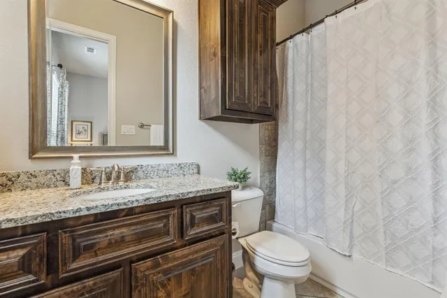 a bathroom with a granite countertop toilet sink and mirror