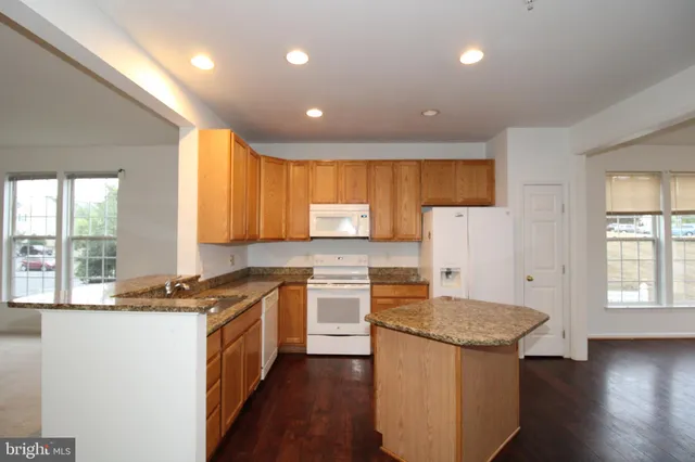 a kitchen with a sink appliances cabinets and a large window