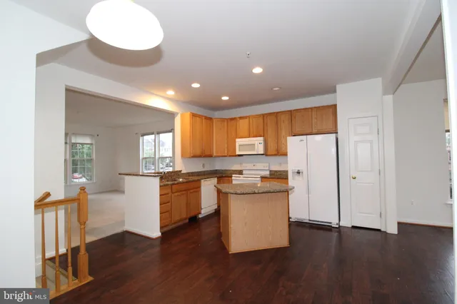 a kitchen with stainless steel appliances a refrigerator and wooden floors