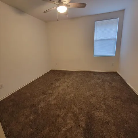 an empty room with a fan and a window