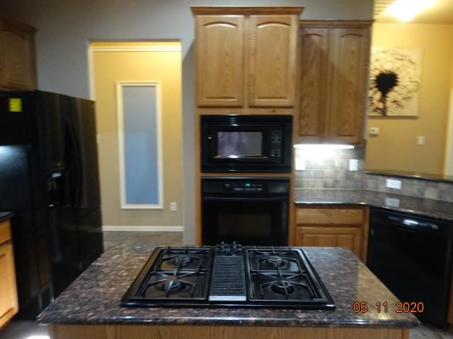 15785 Scenic Road Frisco, TX 75035 - Photo 9 of 21 a kitchen with wooden cabinets and a stove top oven