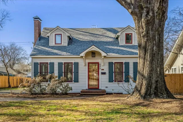 a view of a brick house with large windows and a large tree