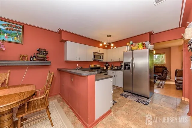 a kitchen with stainless steel appliances granite countertop a refrigerator a sink a stove and white cabinets