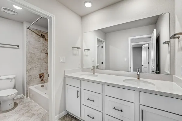 a bathroom with a granite countertop sink a toilet a mirror and shower