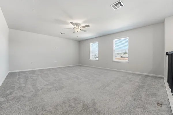 an empty room with windows and ceiling fan