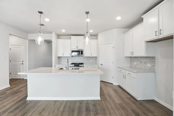 a large white kitchen with kitchen island a stove a sink dishwasher and a refrigerator with wooden floor