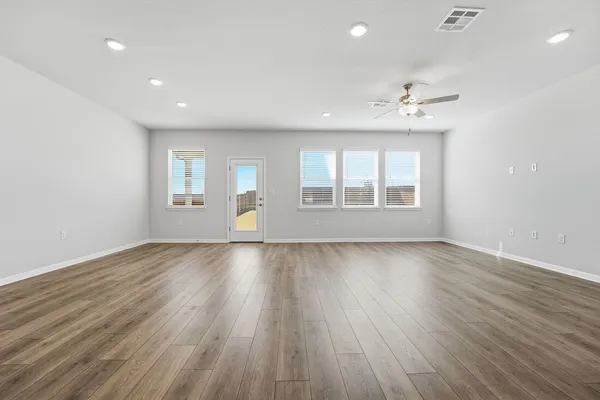 an empty room with wooden floor and windows