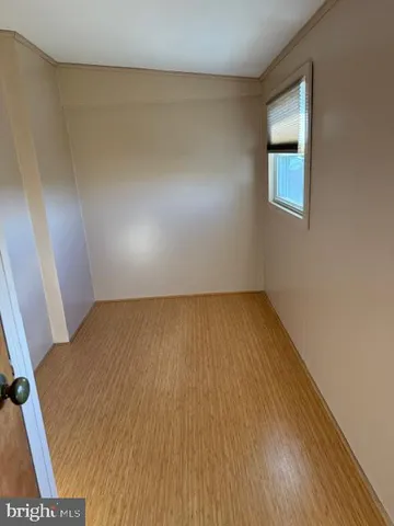 a view of an empty room with wooden floor and cabinets