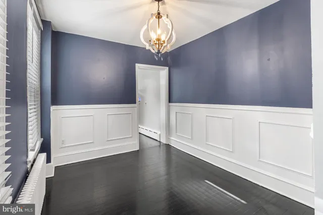 a view of an empty room with wooden floor and cabinet