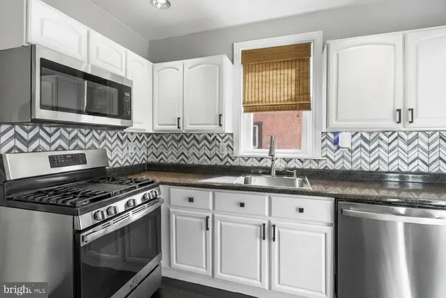a kitchen with granite countertop a sink stove and microwave
