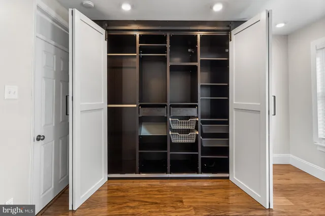 a view of an empty room with wooden floor and closet