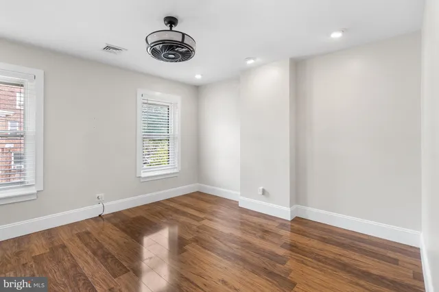 an empty room with wooden floor and windows